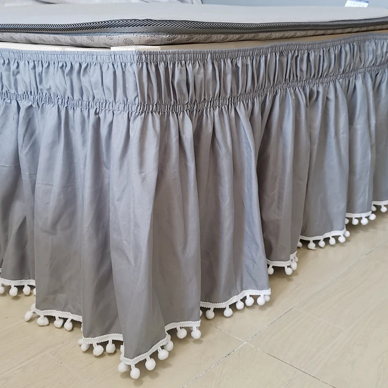 Gray elastic bed skirt with decorative white fringe trim