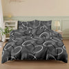 A dark gray printed quilt set featuring concentric white and gray circular patterns on a bed.