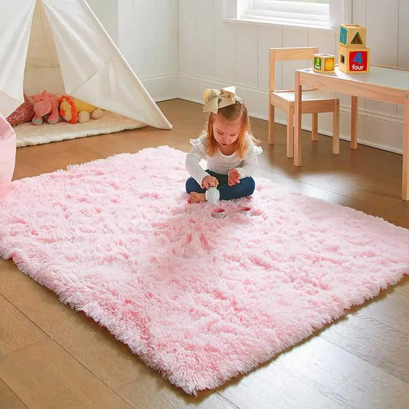 A young girl is playing with colorful plastic toys on a pink shag rug in a bright room.