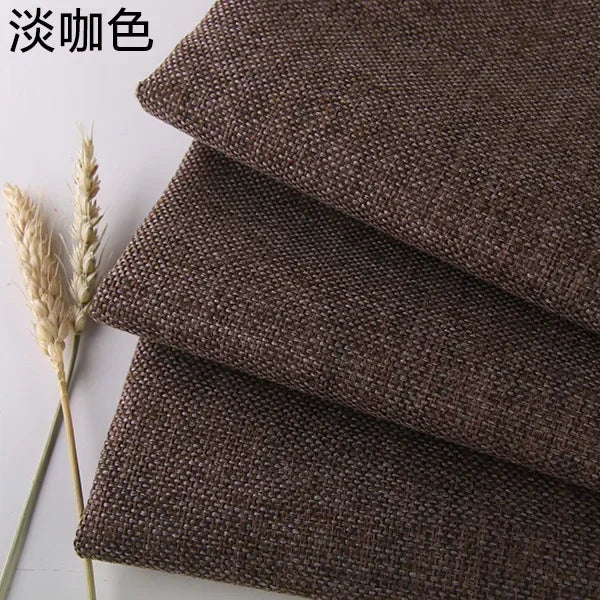 Stack of dark brown coarse linen and cotton fabric squares with dried wheat stalks.