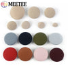 A set of round fabric-covered shank buttons in various shades of beige, gray, black, and reddish-brown.