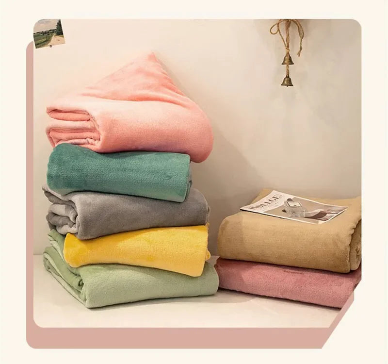 A stack of various colored flannel towels, including pink, teal, gray, yellow, and beige, displayed on a white surface.