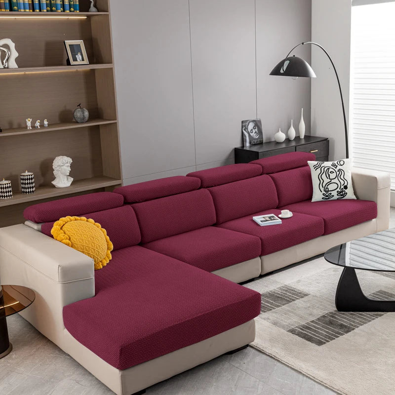 A modern, deep magenta sofa with light beige cushions and a patterned throw pillow in a living room setting.