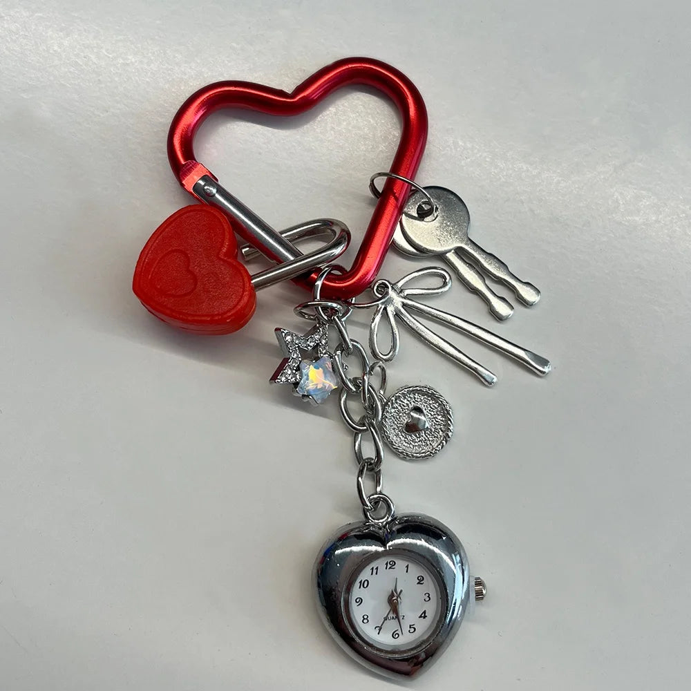 A red heart shaped keychain featuring a silver pocket watch with an adjustable clock face.
