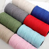 A collection of medium-thick hand-woven cotton yarn in various colors including gray, olive green, blue, red, and pink.