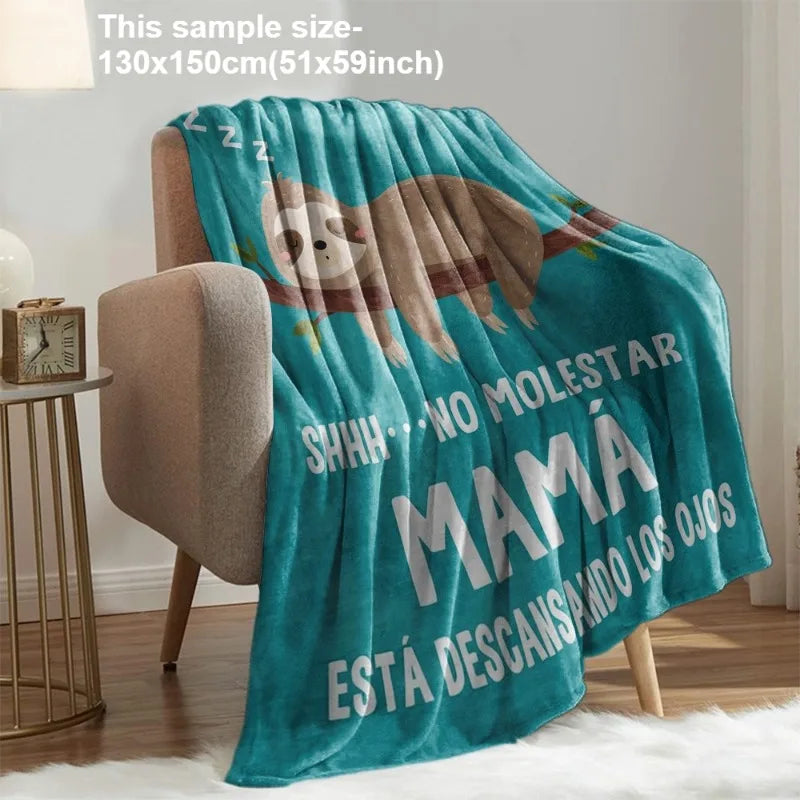 A teal knit throw blanket featuring a graphic design with text that reads 'SHHH NO MOLESTAR MAMA ESTÁ DESCANSANDO LOS OJOS'