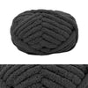 A dark gray hand-knitted wool finger line scarf in a tightly coiled ball.