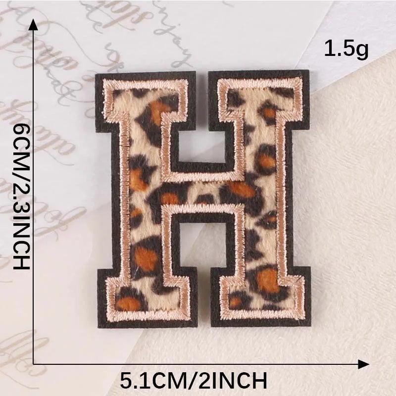 A pair of black iron-on patches shaped like the letter H with a leopard print design.