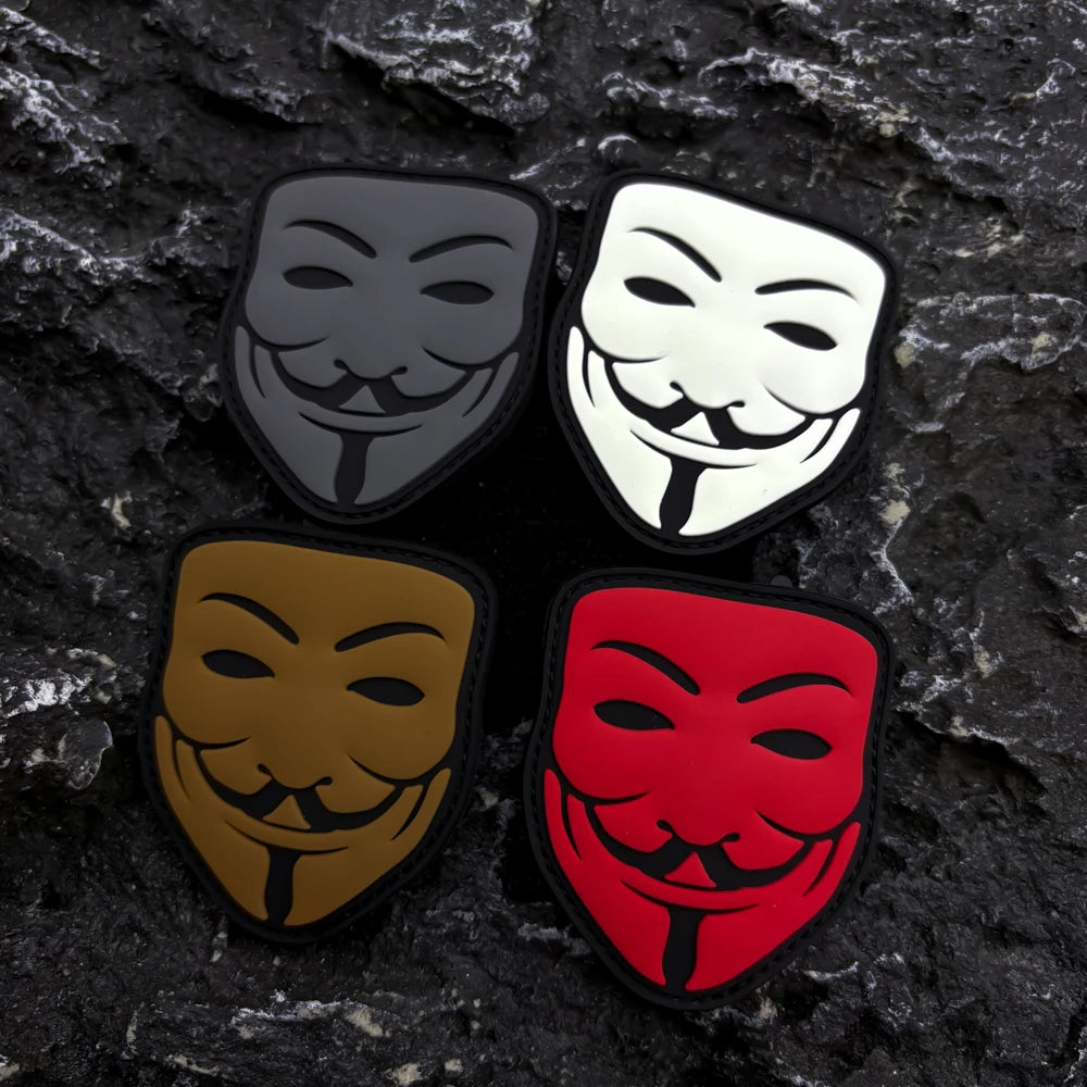 Three embroidered patches featuring smiley faces in black, white, and red on a dark stone background.