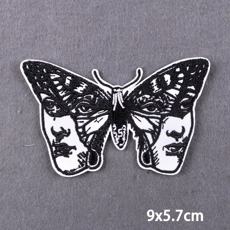 Black and white embroidered patch featuring a stylized skull design.