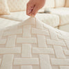 A hand is touching a beige woven jacquard plush sofa cushion cover with a geometric pattern.