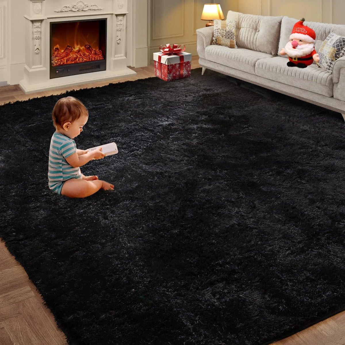 A toddler sits on a black ultra-soft plush living room rug in front of a light-colored sofa and fireplace.