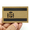 A rectangular tactical patch featuring a woven gold fabric with black stripes and an emblem.