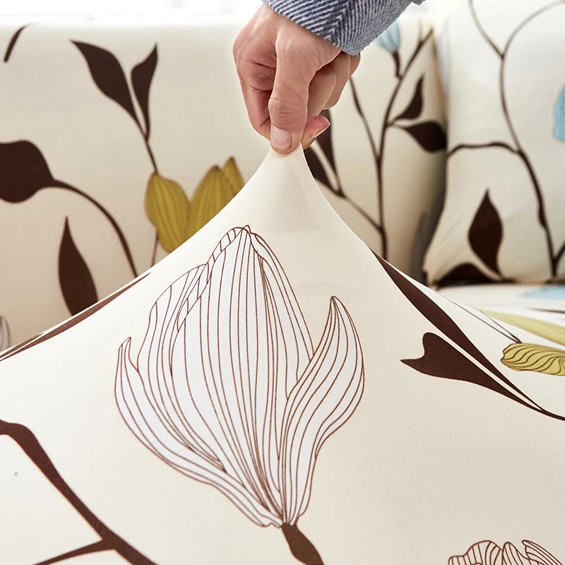 A hand is adjusting a stylish printed sofa protector cover featuring a brown, vertical floral design on a cream background.