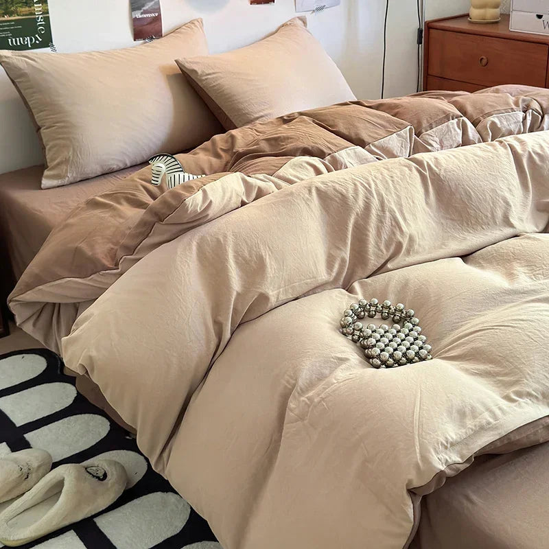A beige quilt bedding set with layered pillows and a decorative beaded bracelet on the duvet.