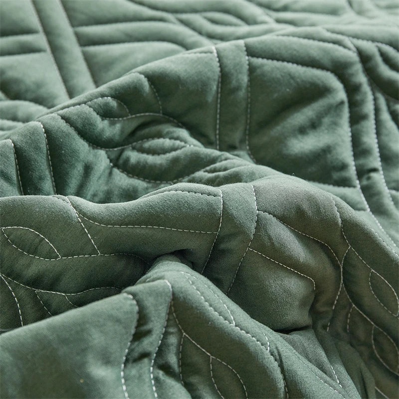 A close-up of a dark olive green quilted fabric, likely a lightweight queen quilt bedding set.