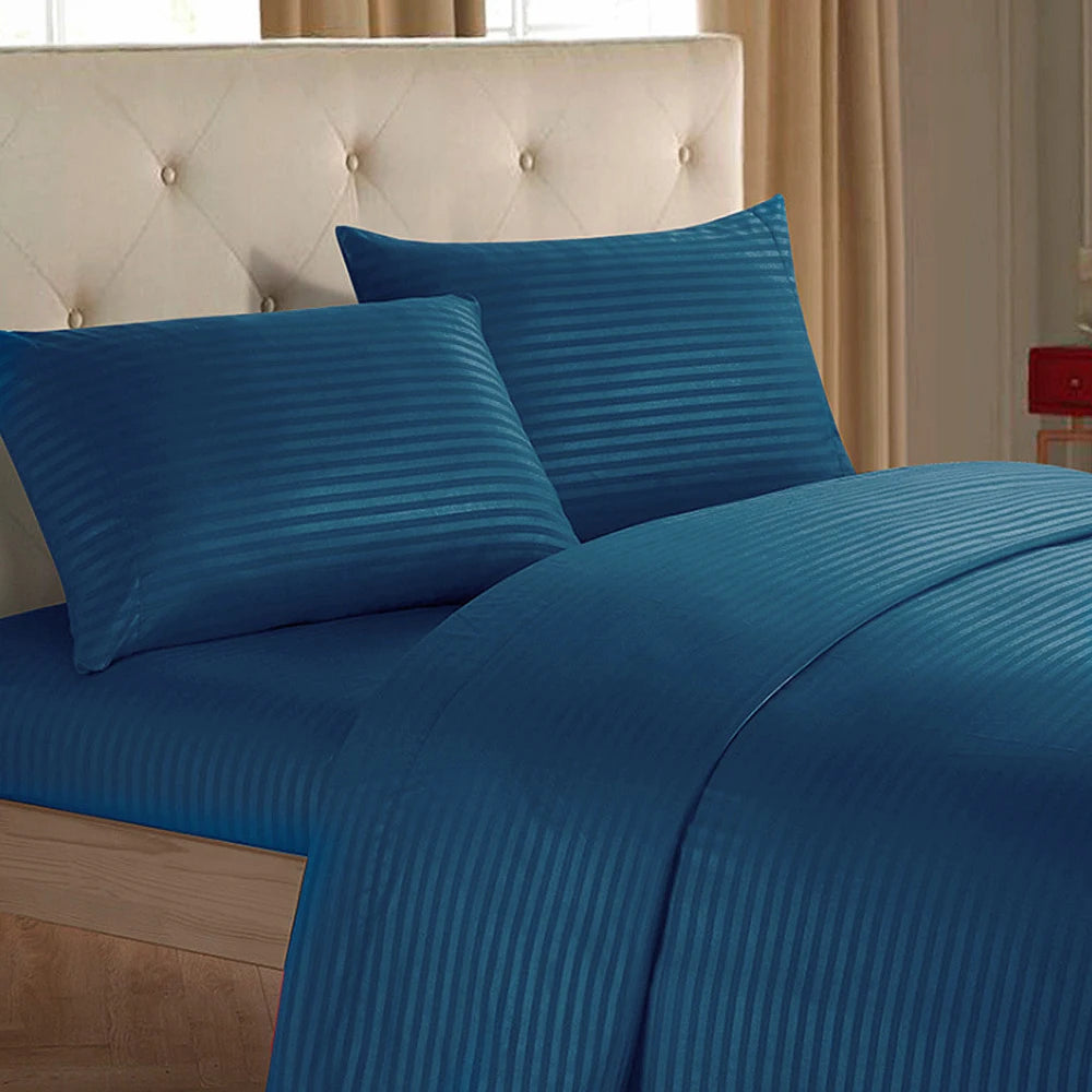 A close-up of a royal blue striped bedding set featuring a tufted headboard and flowing duvet.