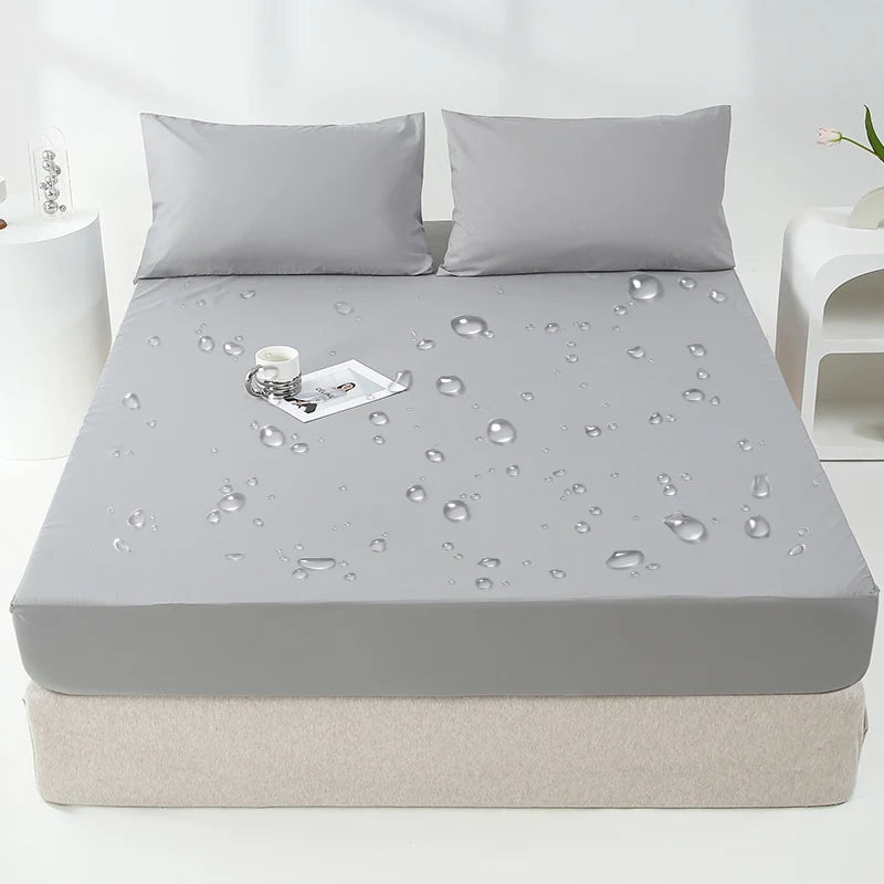 A gray waterproof mattress and bed protector sheet is shown on a mattress, with water droplets visible on the surface.