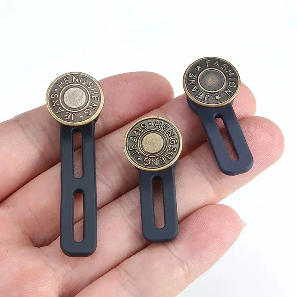 A hand holds three universal waist extender buttons for jeans and pants, featuring a gold-toned finish.