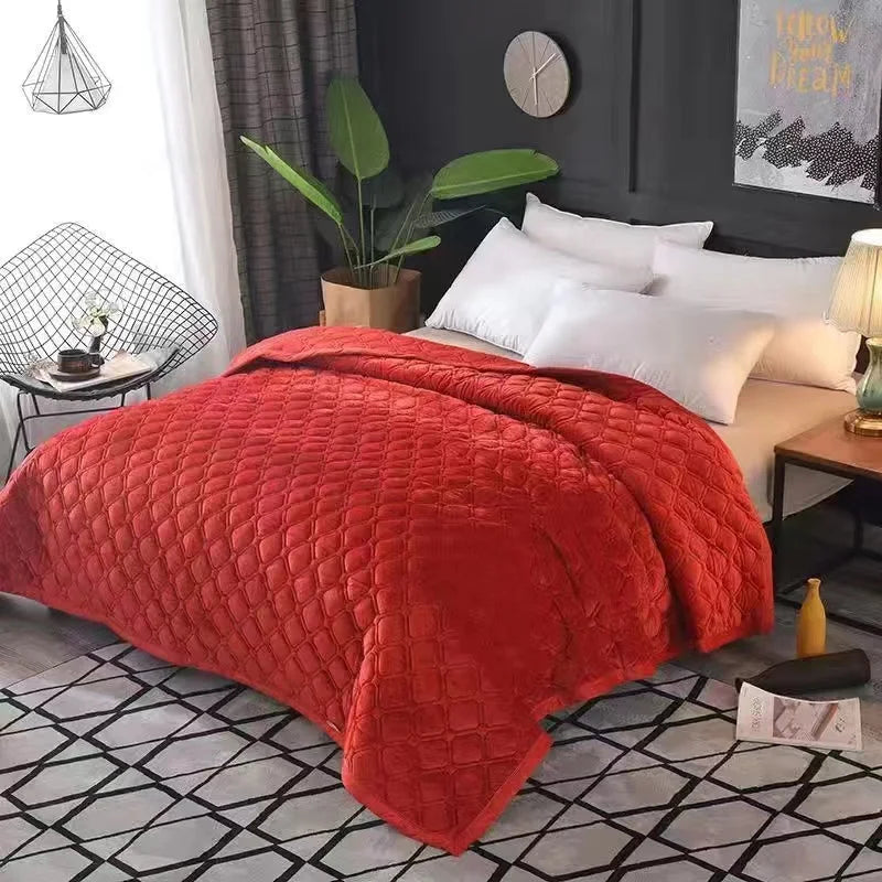 A plush red velvet quilted bed cover blanket draped on a bed in a modern room.