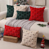 A collection of red and green Christmas tree plush throw pillow covers displayed on a white sofa.