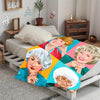 A colorful retro pop art flannel blanket featuring portraits of smiling women in various shades of pink, green, and blue.