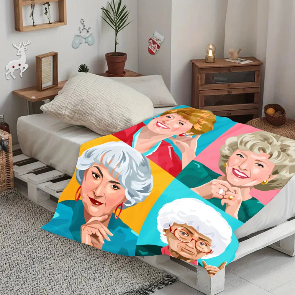 A colorful retro pop art flannel blanket featuring portraits of smiling women in various shades of pink, green, and blue.