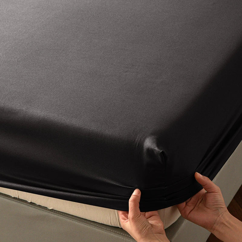 A close-up of a dark gray soft touch microfiber fitted sheet being held, showing its texture and fit.
