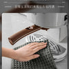 A hand is wiping a coffee machine with a gray microfiber cleaning towel.