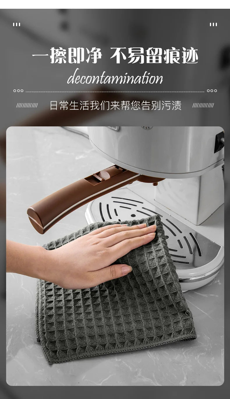 A hand is wiping a coffee machine with a gray microfiber cleaning towel.