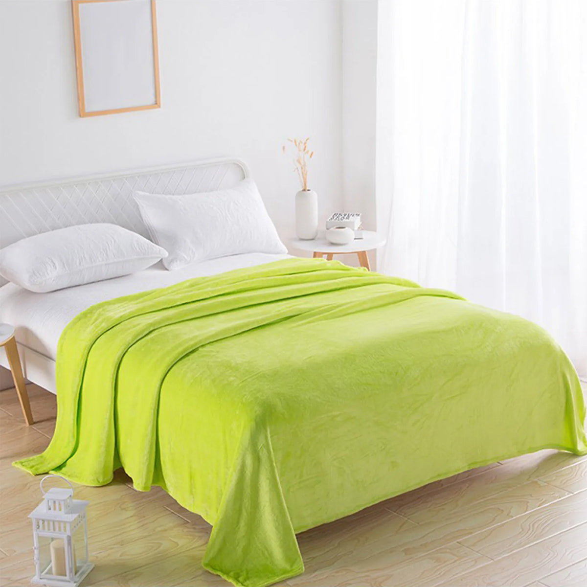 A bright lime green coral fleece throw blanket draped over a white bed.