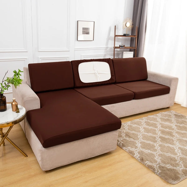 A brown solid elastic sofa cushion slipcover on a light beige sofa with a decorative rug.