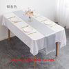 A white satin table runner set for dining featuring gold cutlery and pink floral accents on a wooden table.