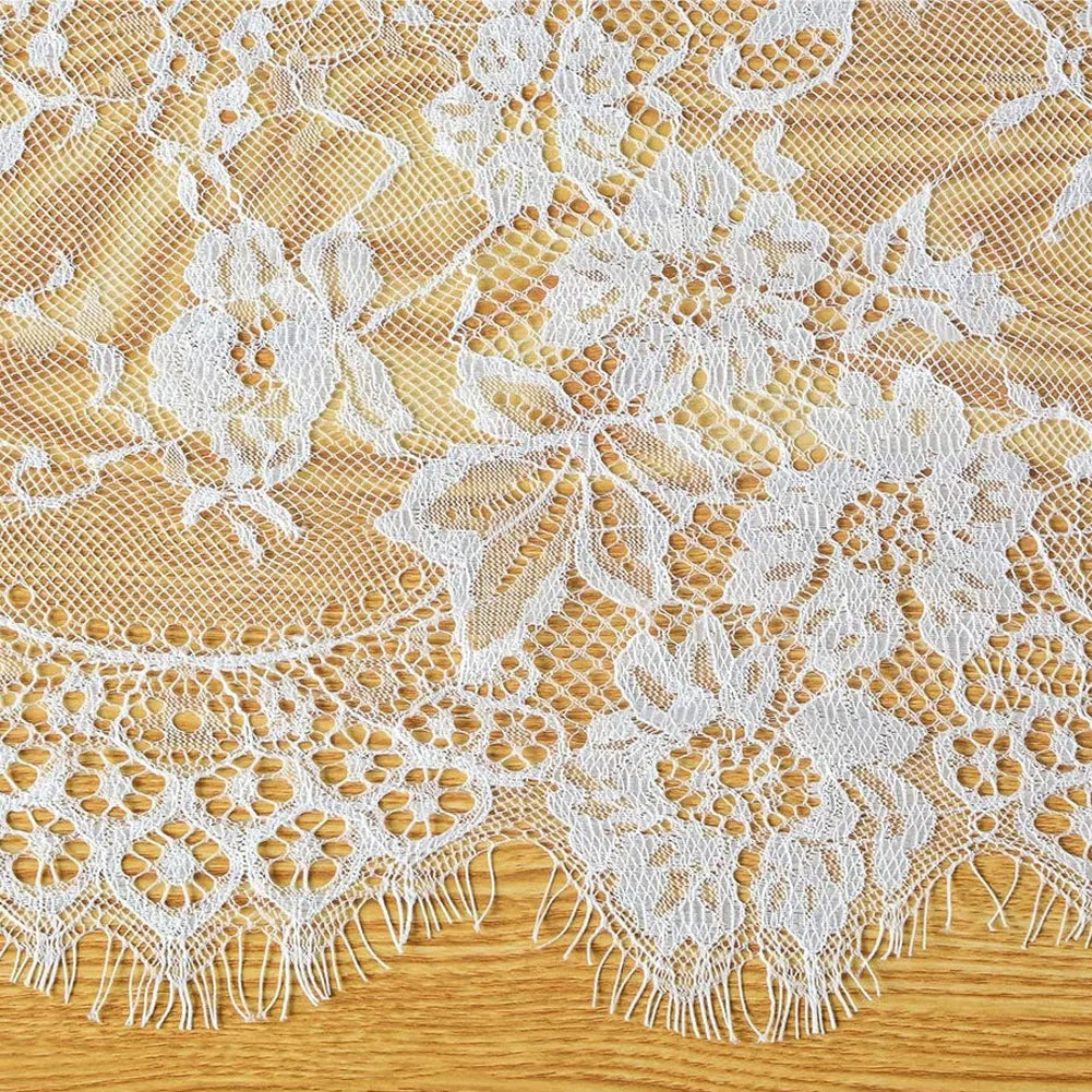 White embroidered floral lace table runner with scalloped edges on a wooden surface.