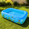 A bright blue inflatable pool with colorful tropical designs is placed on a green lawn.