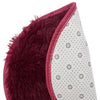 A close-up of a deep burgundy shaggy round area rug with white polka dots and red trim.