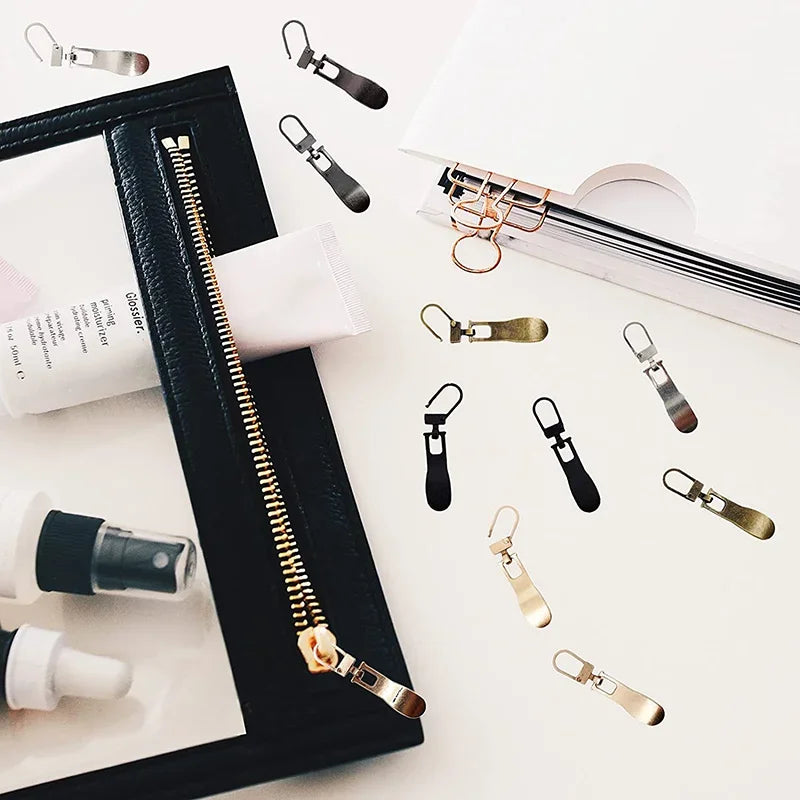 A collection of replacement metal zipper pulls in various finishes and sizes displayed on a white background.