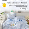 A light blue patterned summer quilt set is displayed on a bed, emphasizing soft and gentle care.