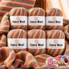 A set of six balls of fancy wool yarn in various striped colors and textures for knitting and crochet projects.