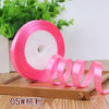 Pink satin ribbon roll with a pink core displayed on a wooden surface.