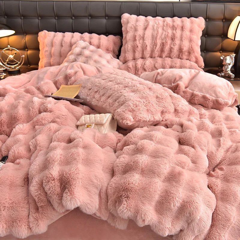 A pink plush rabbit hair bedding set featuring a fluffy duvet and pillows on a dark upholstered bed.