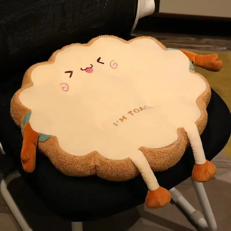 A plush cartoon toast shaped seat cushion with smiling features resting on a black chair.