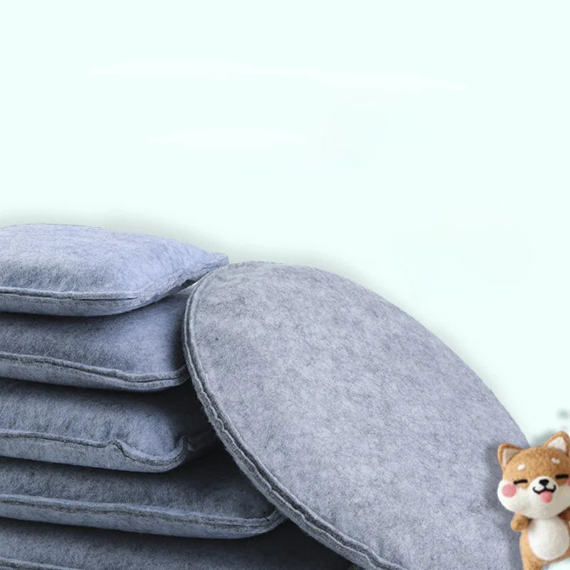 A stack of gray needle felting mat pads next to a small, fluffy dog.