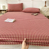 A close-up view of a red and cream checkered fitted sheet with matching pillowcases on a bed.