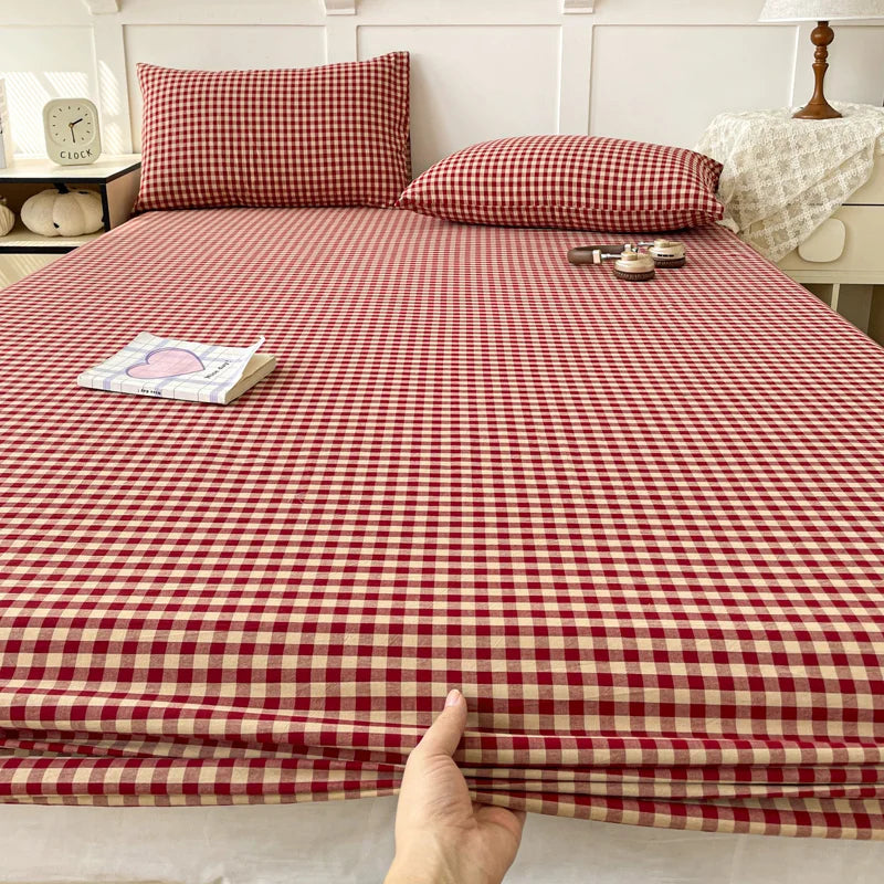 A close-up view of a red and cream checkered fitted sheet with matching pillowcases on a bed.