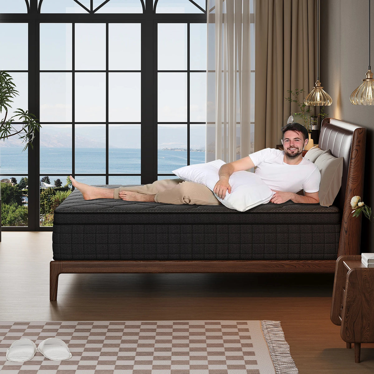 A man lies on a dark brown bed in a modern room with large windows overlooking the ocean.