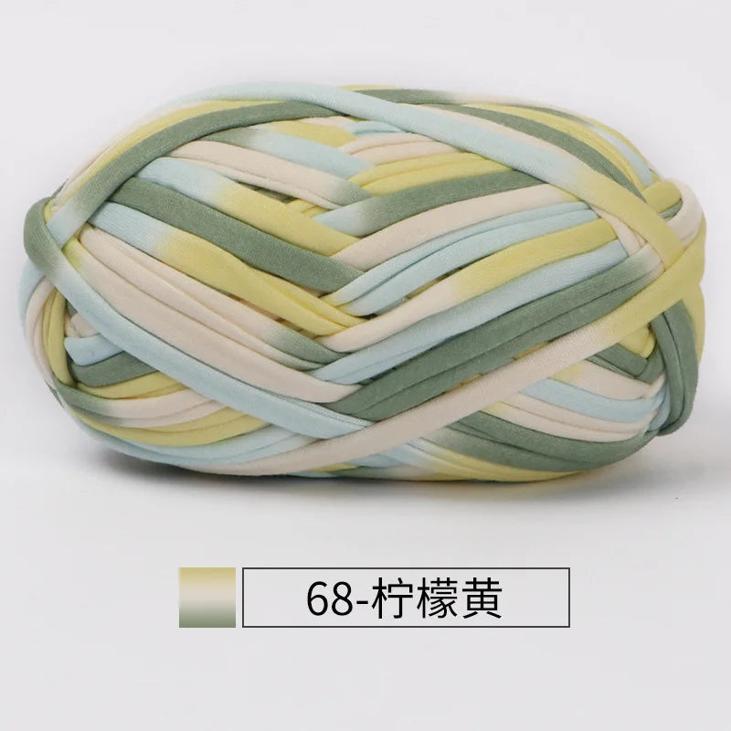 A ball of hand-dyed fabric strip yarn featuring shades of yellow, green, and beige.