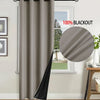 A floor-length gray blackout curtain hanging on a rod next to a window.
