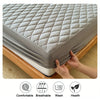 A gray waterproof mattress protector fitted sheet is shown being placed onto a wooden bed frame.