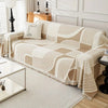 A beige and white striped sofa cover featuring a geometric pattern and a simple face pillow on a light-colored sofa.